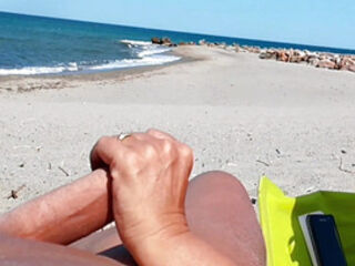 She shows her ass on the beach of Cap d'Agde and jerks off her pussy and then her boyfriend's cock with voyeurs